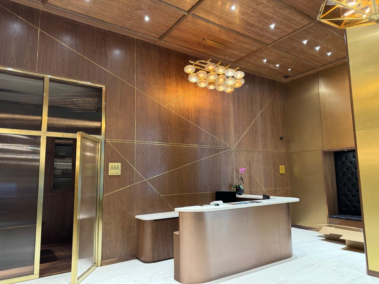 Recepción con acabados de madera y vidrio dorado